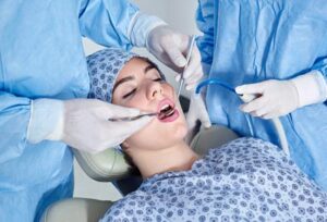 Woman in a dental chair getting a procedure looking very relaxed after being sedated. 